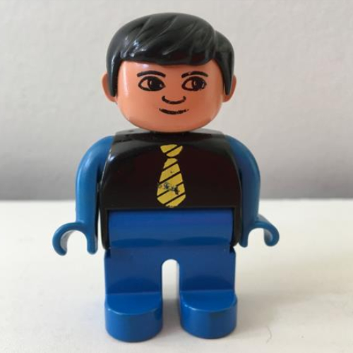 Visuel indicatif Rebrickable de Figurine Duplo, tôt, avec cheveux courts séparés noir, jambes bleues, cravate jaune, bras bleus, pas de motif imprimé blanc dans les yeux (Duplo Figure, Early, with Short Parted Hair Black, Blue Legs, Yellow Tie, Blue Arms, no White in Eyes Print)